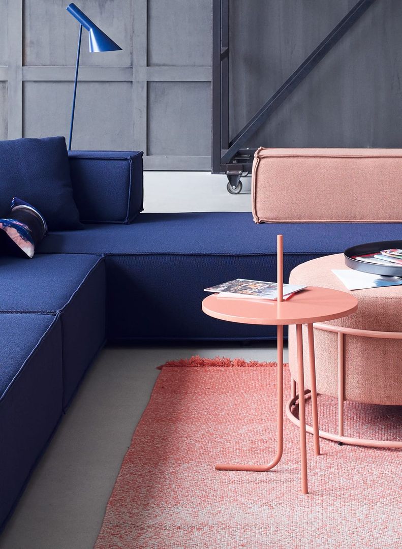 Moderner, runder Bond Beistelltisch von Cor in Lachsrosa neben Sofa und Teppich.