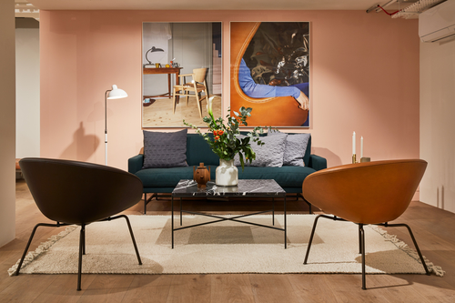 Wohnzimmer-Szene mit Fritz Hansen Couchtisch Planner, Sofa, Sesseln und Dekoration auf einem Teppich.