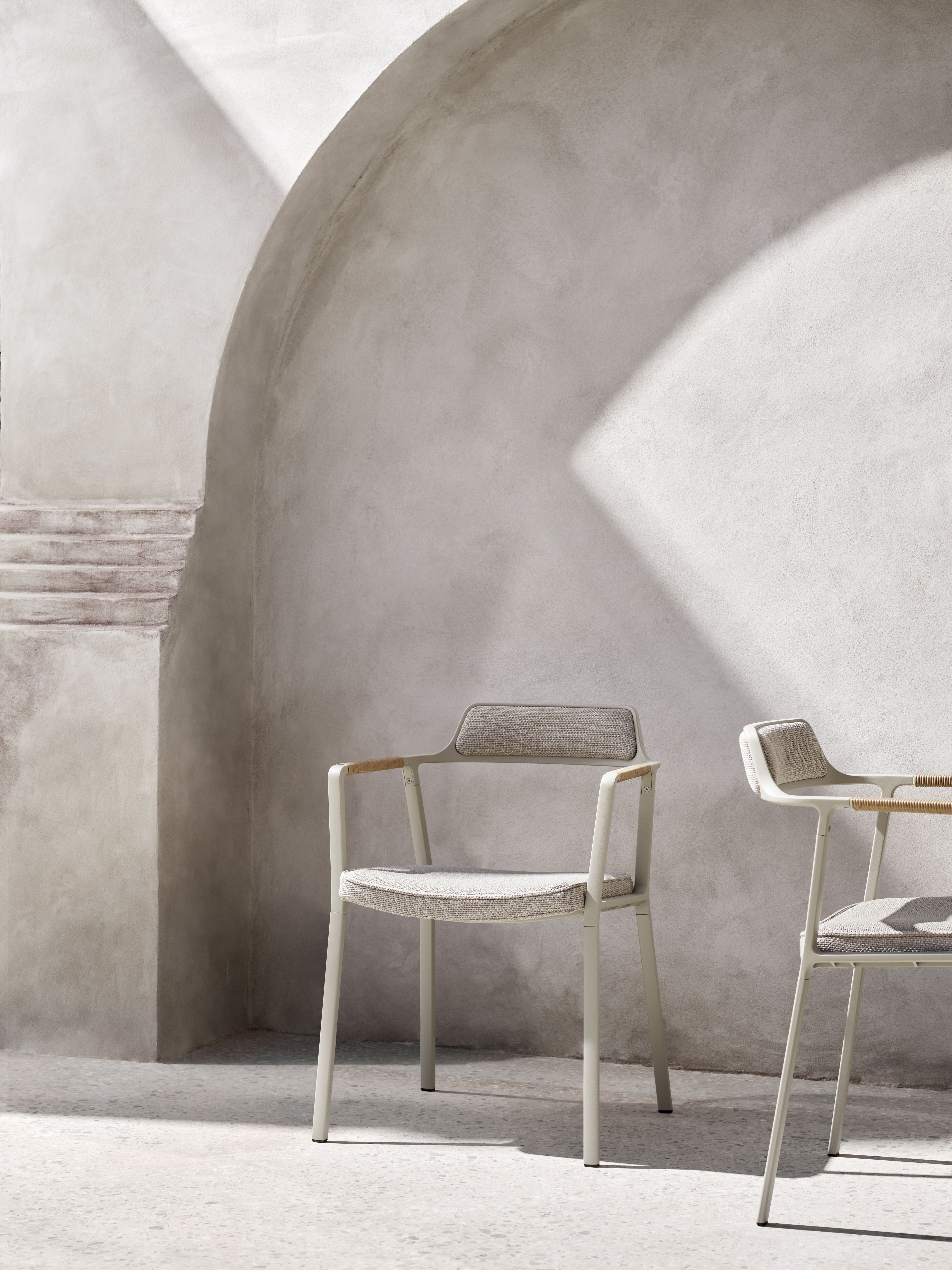 Zwei Vipp Open-Air Outdoor Stühle in Beige vor einer hellen Betonwand mit Treppe.