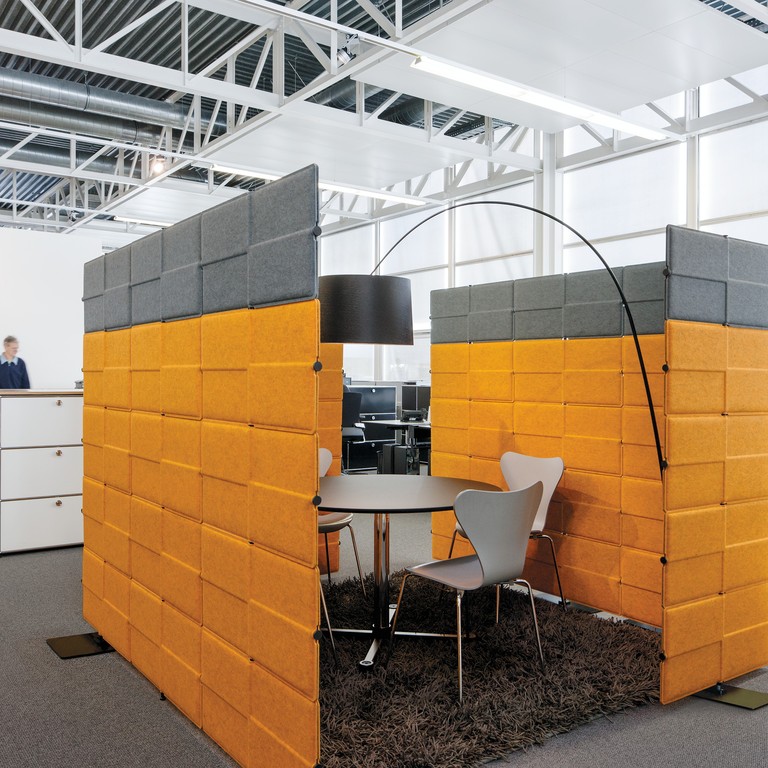 Büro mit USM Haller Privacy Panels in Grau und Orange, die einen Besprechungsbereich abtrennen.