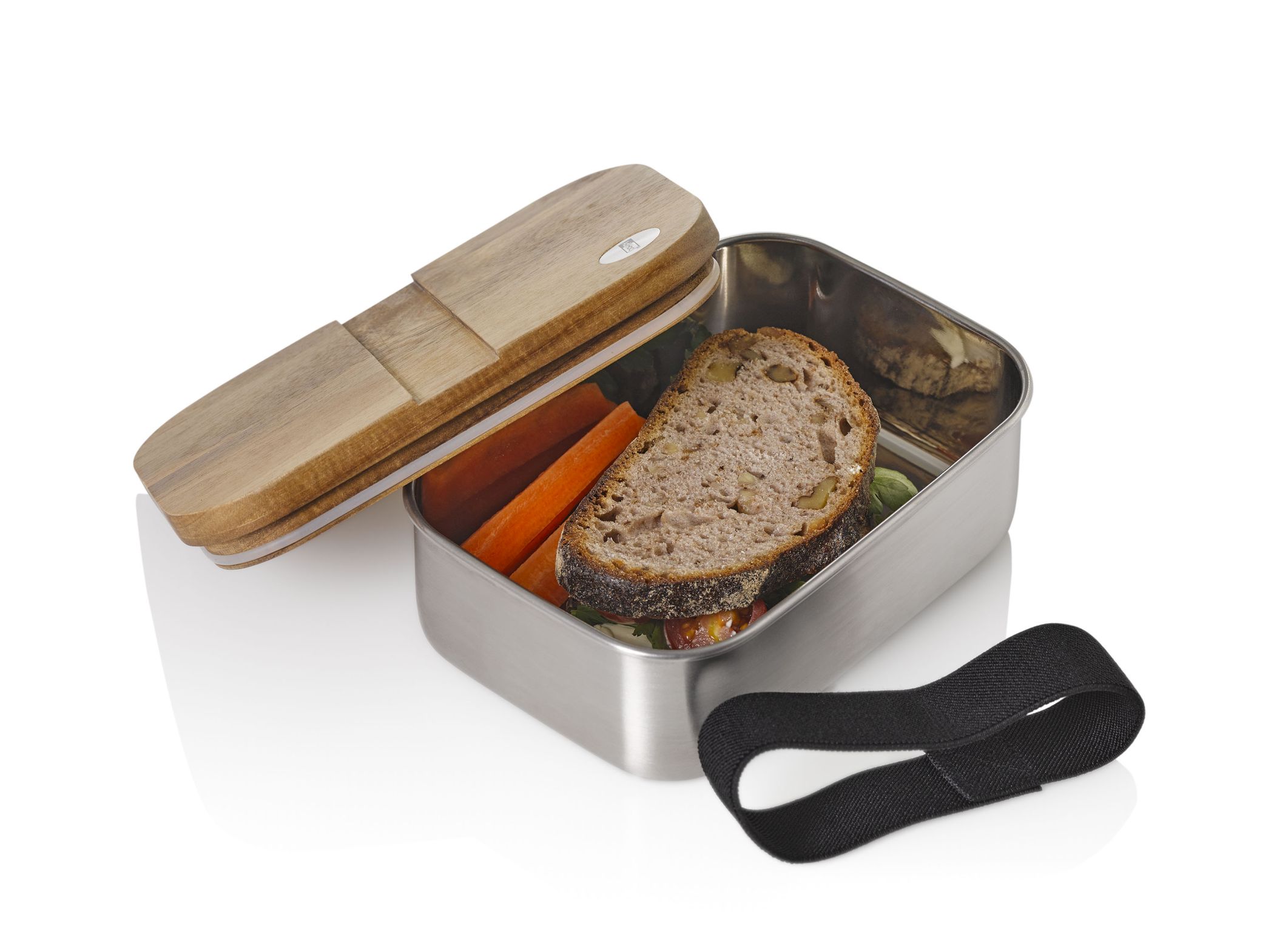 Geöffnete Cotto Lunchbox aus Edelstahl mit Holzdeckel, gefüllt mit Brot, Karotten und Gummiband.