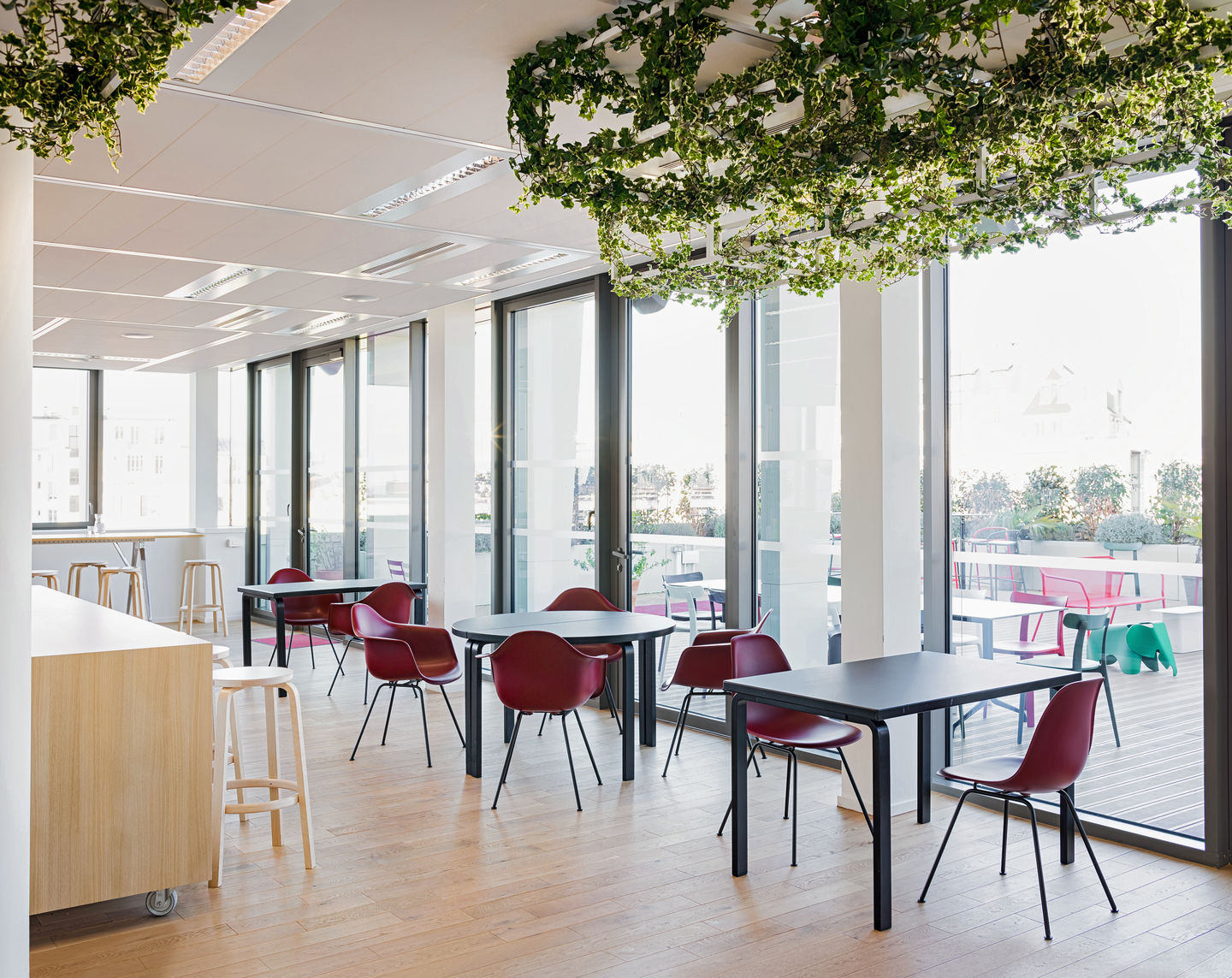 Innenraum mit Eames Stühlen von Vitra in Rot, Tischen und viel Tageslicht.