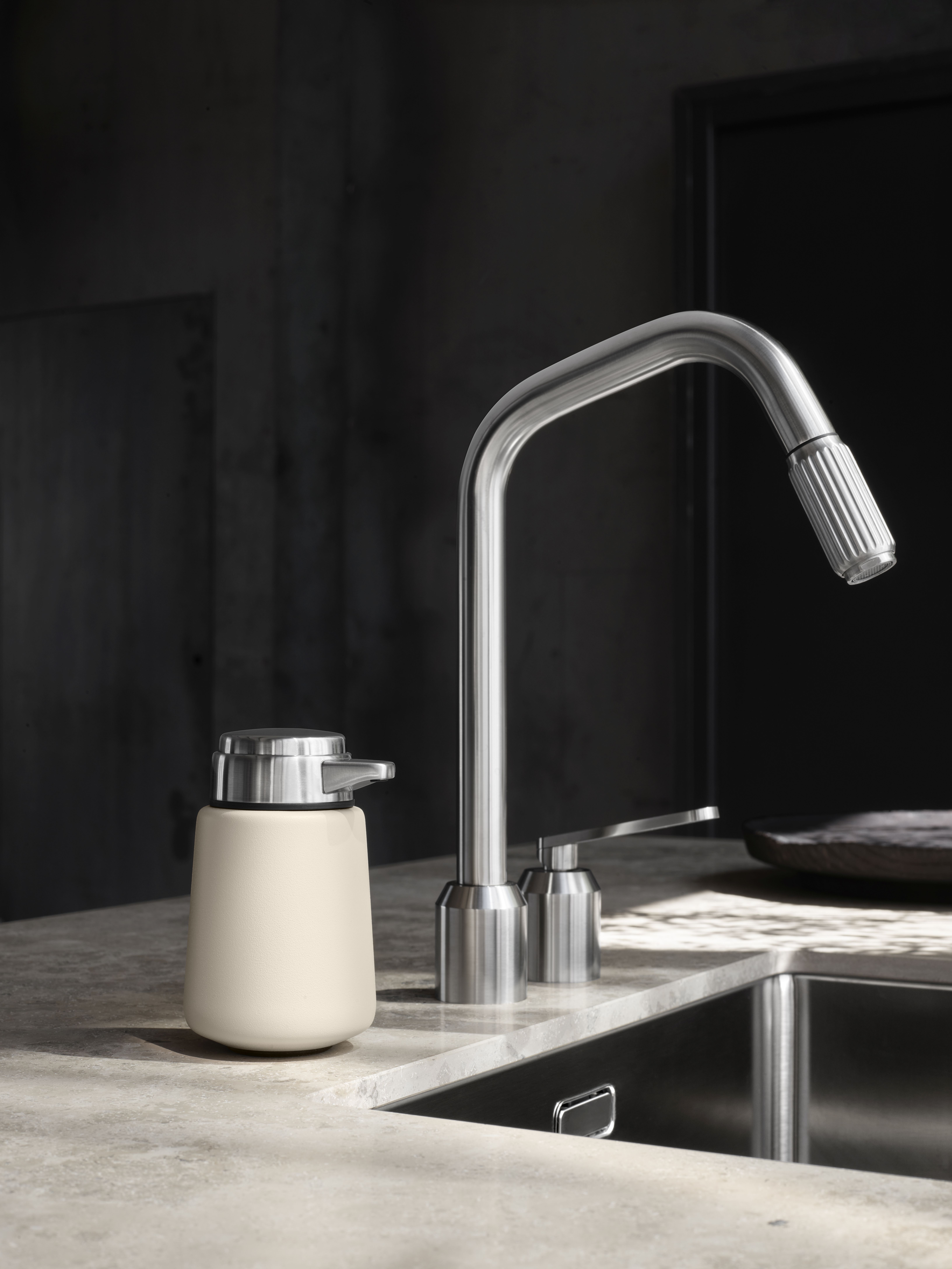 Beiger Vipp Seifenspender aus Edelstahl in moderner Küche neben Spüle und Armatur.