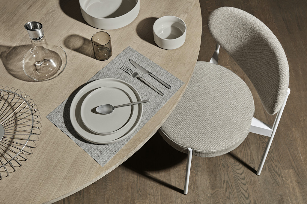 Nahaufnahme: Tischgedeck mit Blomus Stella Besteck, Teller, Glas, Karaffe und Stuhl. Modernes Besteck-Set für stilvolles Essen.