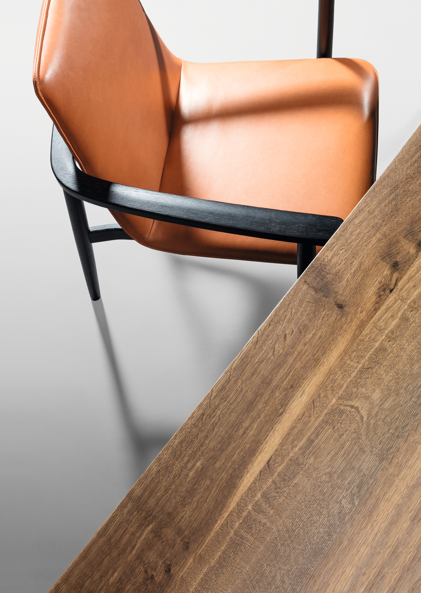 Detailaufnahme Janua S 600 Tischplatte aus Nussbaumholz mit Stuhl und Lederbezug.