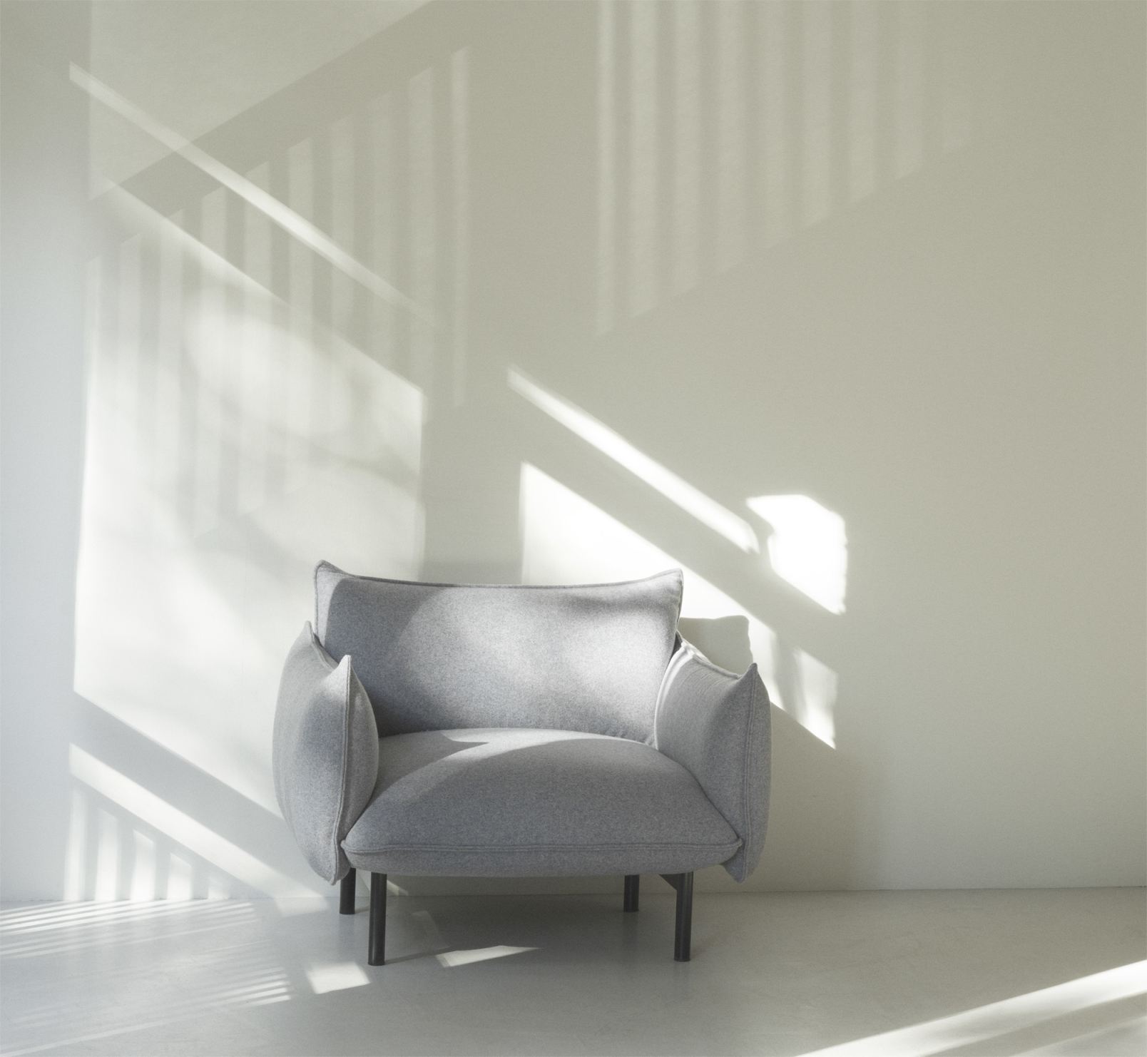 Grauer Ark Lounge Chair Sessel von Normann Copenhagen vor einer weißen Wand mit Schatten.