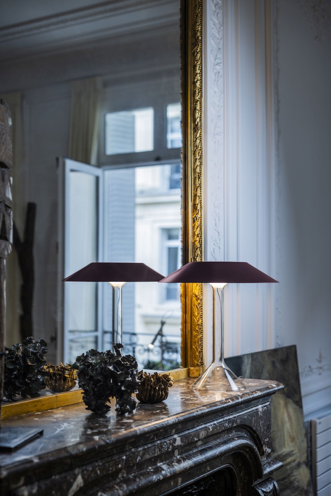 Zwei dunkelrote Chapeaux Tischleuchten von Foscarini auf einem Marmorkamin, stimmungsvolle Beleuchtung.