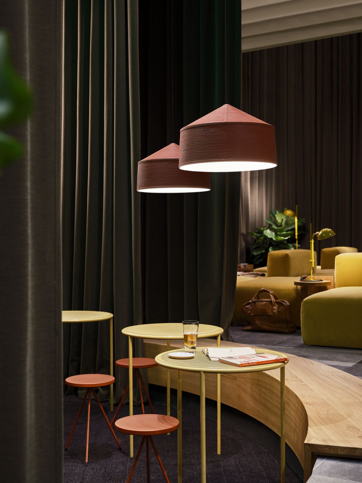 Zwei graue Zenc Pendelleuchten von Marset hängen über Tischen und Stühlen in einem stilvollen Interieur.