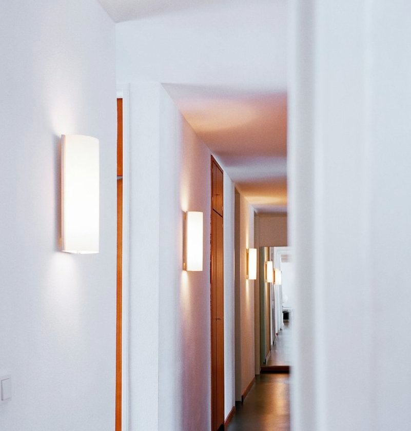 Flur mit mehreren leuchtenden, rechteckigen Club Wandleuchten von Serien Lighting an weißen Wänden.