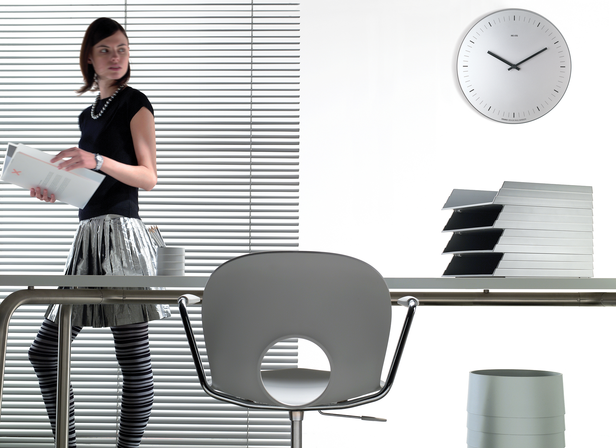 Helle Büroszene mit Orario Wanduhr von Rexite, Edelstahl, ohne Ziffern, modernes Design.