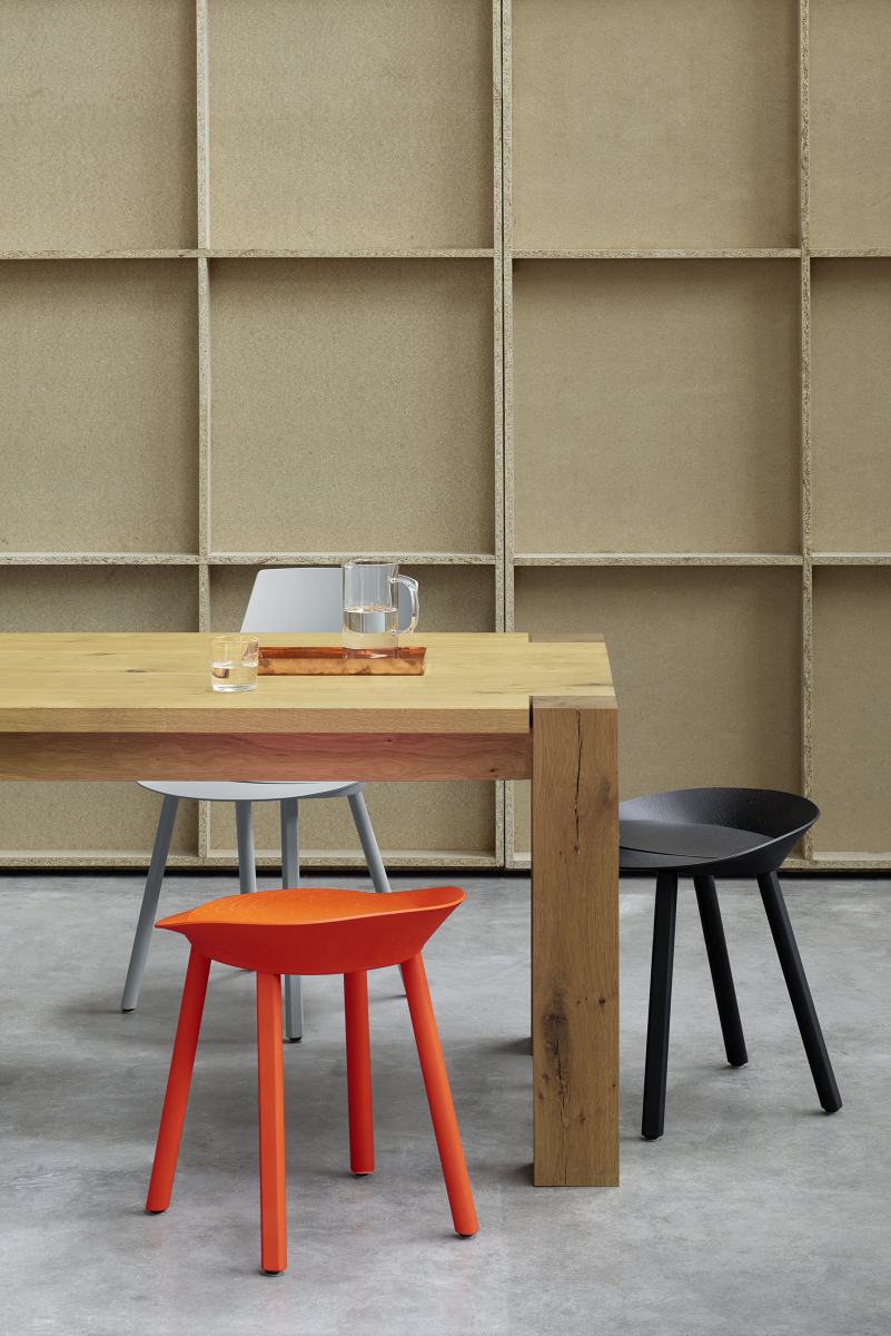 E15 Bigfoot Tisch aus Massivholz mit Stühlen in Orange, Grau und Schwarz.