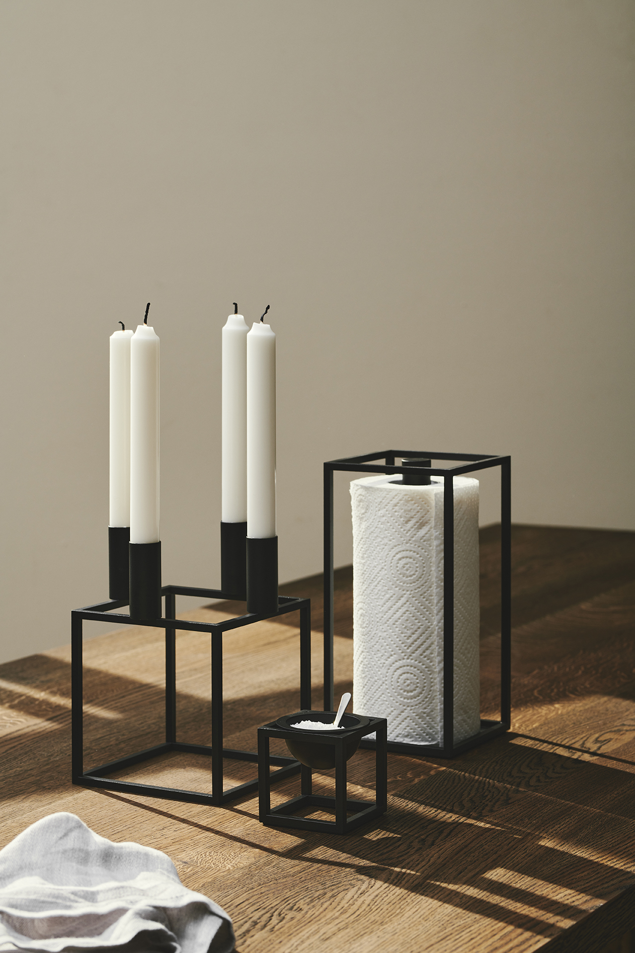 Produktfoto: Schwarzer Kerzenständer, Küchenrollenhalter und Salznapf im minimalistischen Design auf Holztisch.