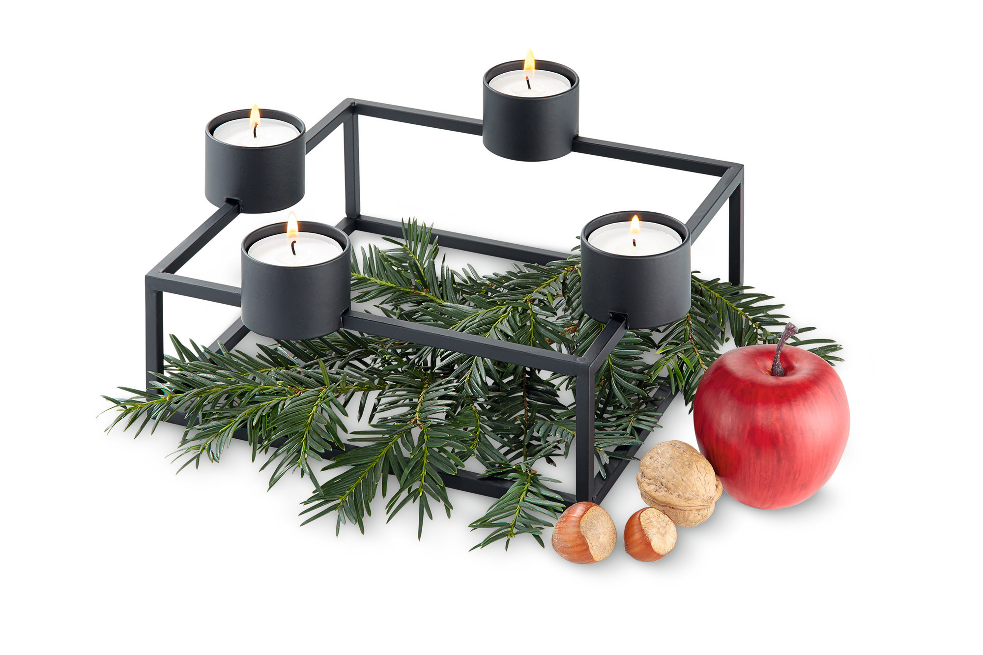 Schwarzer Cubo Kerzenhalter von Philippi mit vier brennenden Kerzen, Tannenzweigen, Apfel und Nüssen.