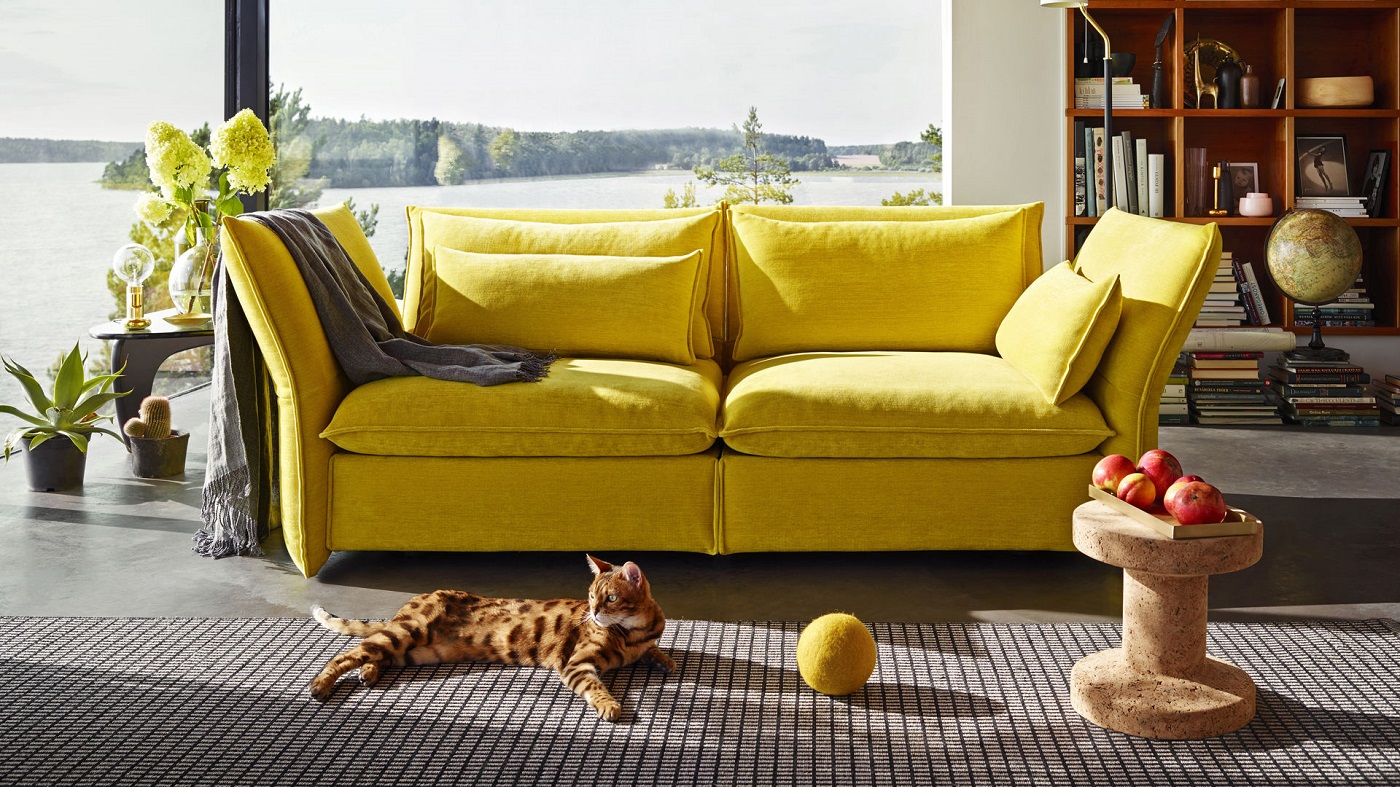 Wohnzimmer mit gelbem Sofa, Katze und Vitra Cork Family Hocker Modell B aus Kork.
