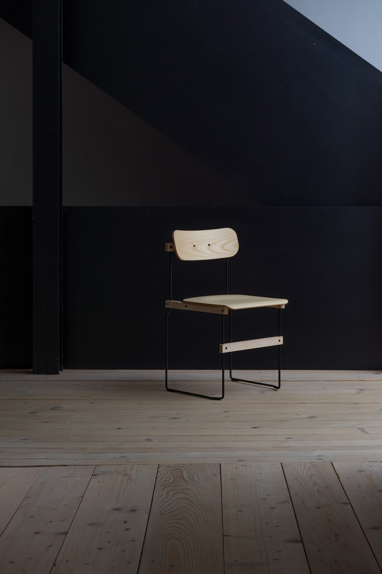Bruto Stuhl von Nils Holger Moormann: Holzstuhl mit schwarzem Metallgestell auf hellem Holzboden.
