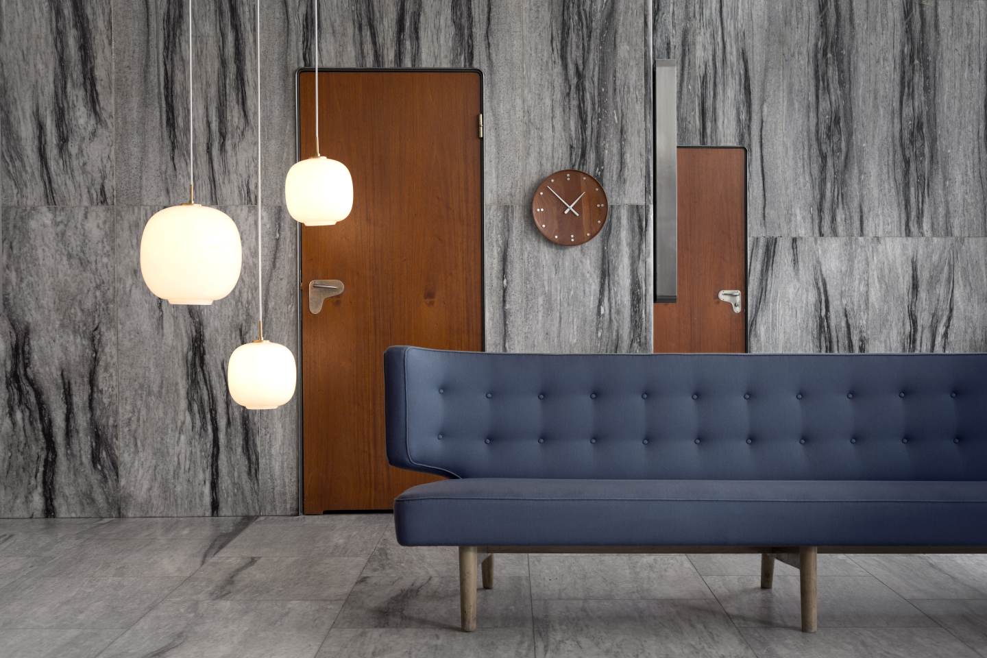 Drei VL45 Radiohus Pendelleuchten von Louis Poulsen über einem blauen Sofa in einem modernen Raum.