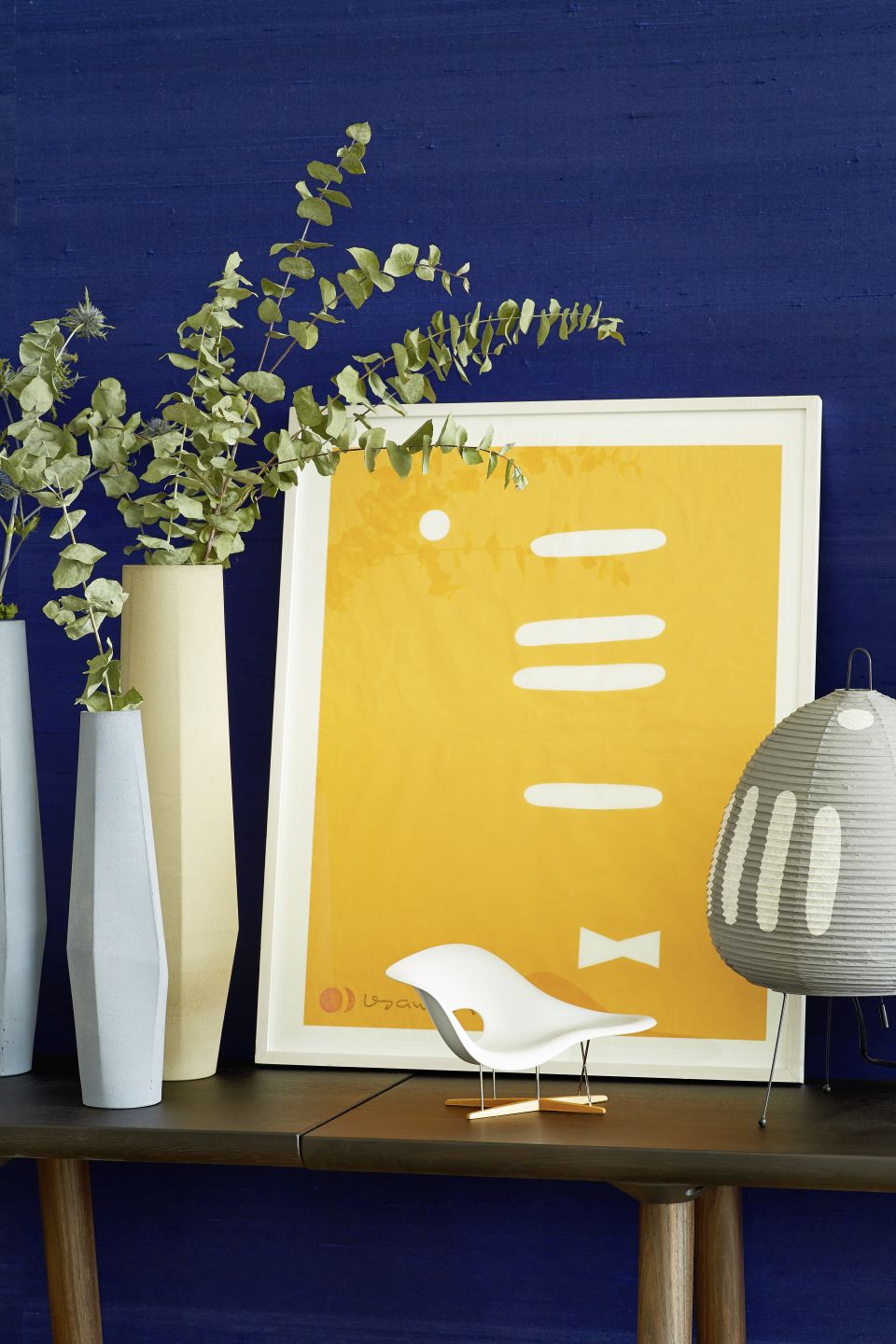 Dekoratives Stillleben mit La Chaise Miniatur von Vitra, Designklassiker und stilvolles Wohnaccessoire auf dunklem Tisch.