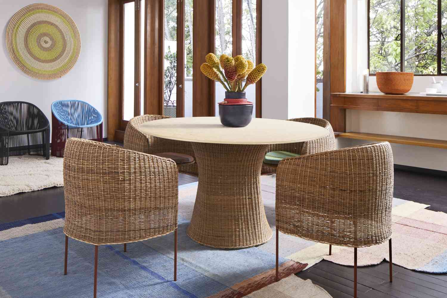 Esstisch aus Rattan mit passenden Stühlen und dekorativer Blumenvase für ein stilvolles Esszimmer.