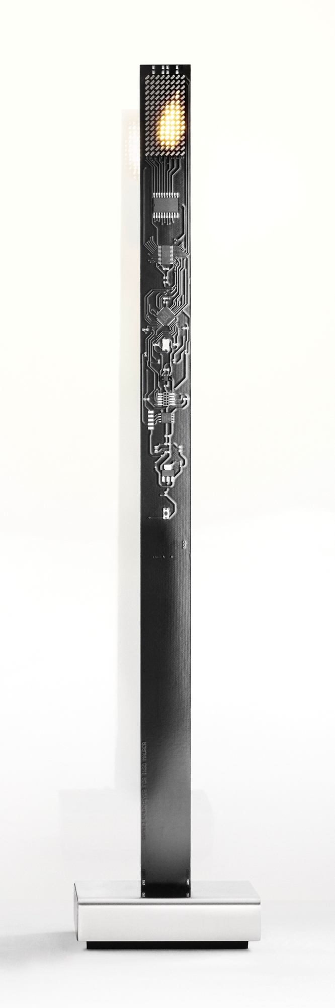 My New Flame Tischleuchte von Ingo Maurer: Schwarze Platine mit LED-Flamme auf silbernem Sockel.