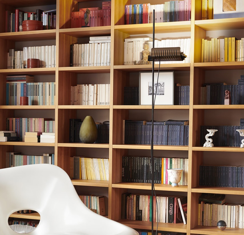 Colombo LED Stehleuchte von Oluce in Bronze/Schwarz vor einem Bücherregal. Designleuchte für Wohnzimmer.