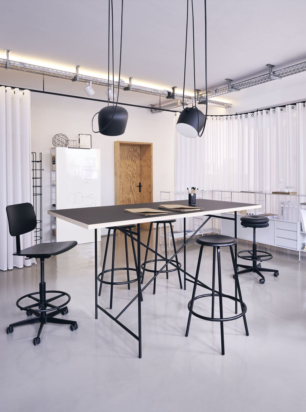 Milla Stehtisch von Richard Lampert mit schwarzen Barhockern in einem modernen Büro.