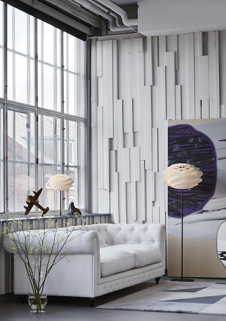 Swirl Stehleuchte von Le Klint in modernem Wohnzimmer mit Sofa und großem Fenster.