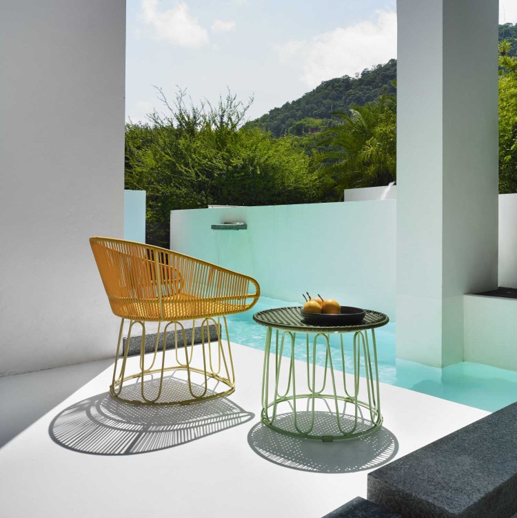 Ames Circo Beistelltisch Outdoor in Grün neben gelbem Rattansessel am Pool. Gartentisch für Terrasse.