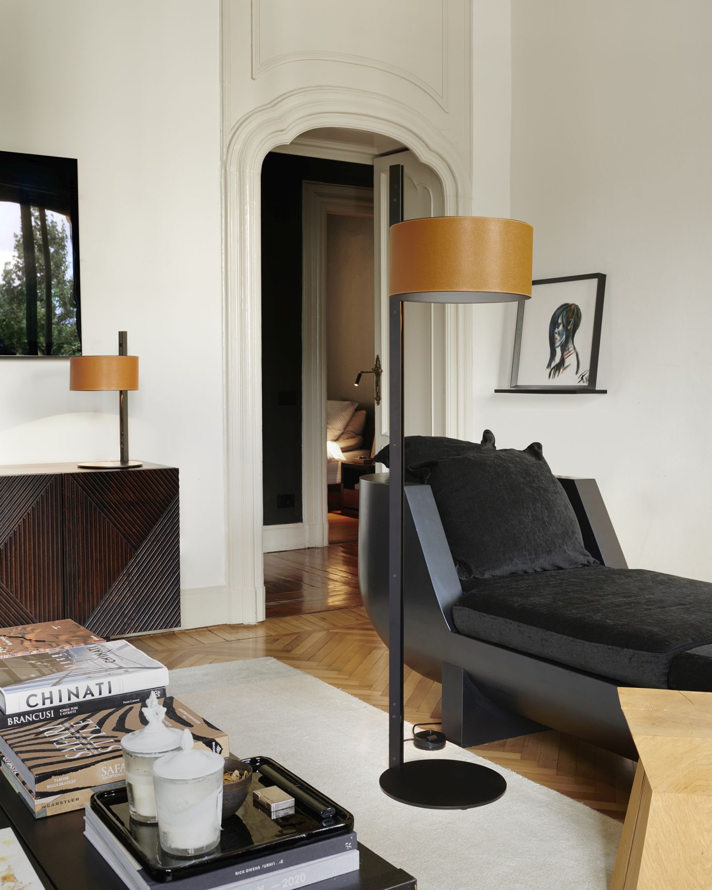 Oluce Stehleuchte Parallel 396 im Wohnzimmer mit beigem Lampenschirm und schwarzem Gestell.