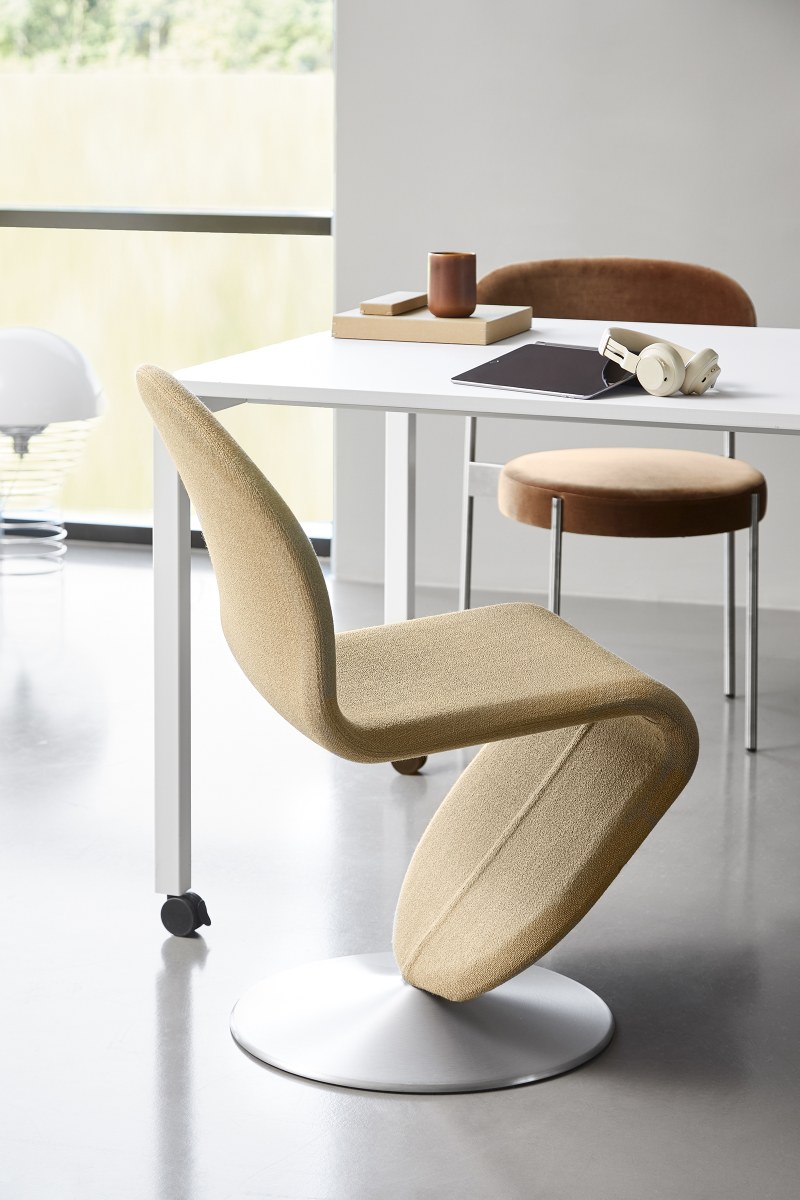 Beiger, ergonomischer Bürostuhl mit Rollen und Drehfuß vor weißem Schreibtisch mit Accessoires.