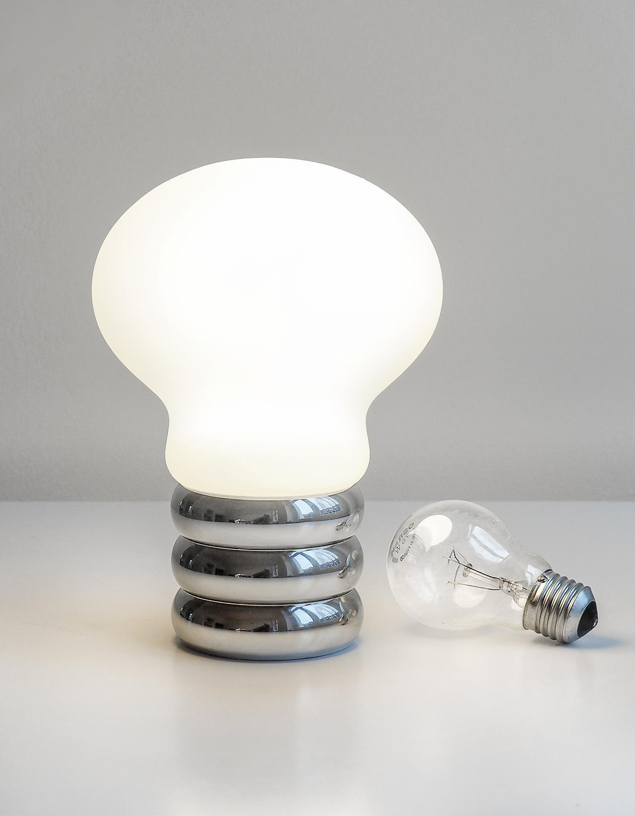 b.bulb Akkuleuchte von Ingo Maurer: Tischleuchte mit USB-Anschluss, glänzendem Chromfuß und leuchtendem Glühbirnen-Design.
