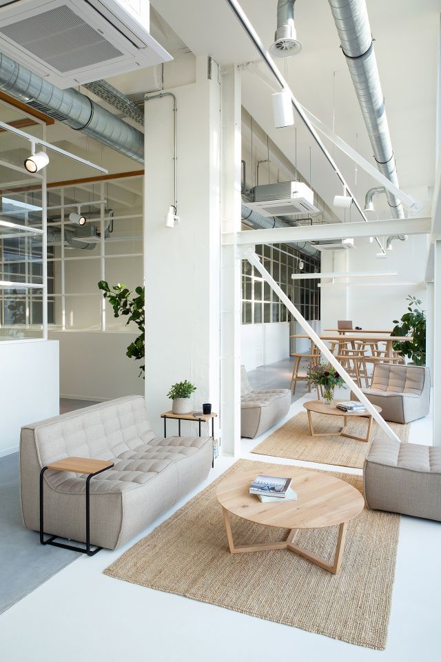 N701 Sofa und Polsterhocker von Ethnicraft in hellem Raum mit Teppich und Holztischen.