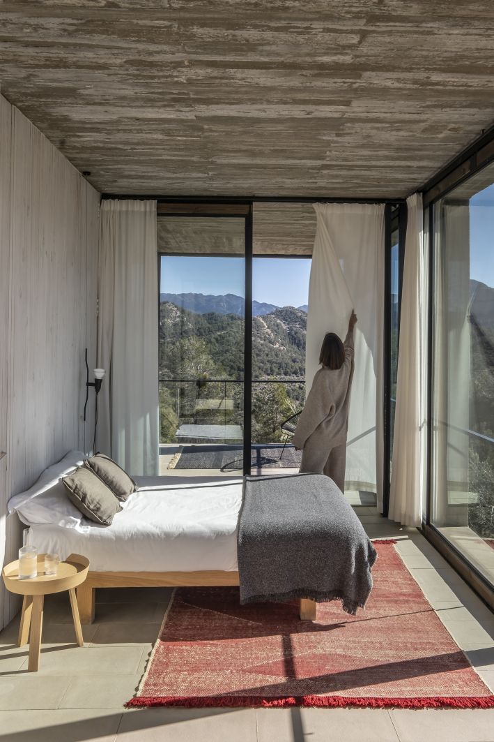 Telares Teppich Pine von Nanimarquina in einem Schlafzimmer mit Bergblick, roter Designer Teppich mit geometrischem Muster.