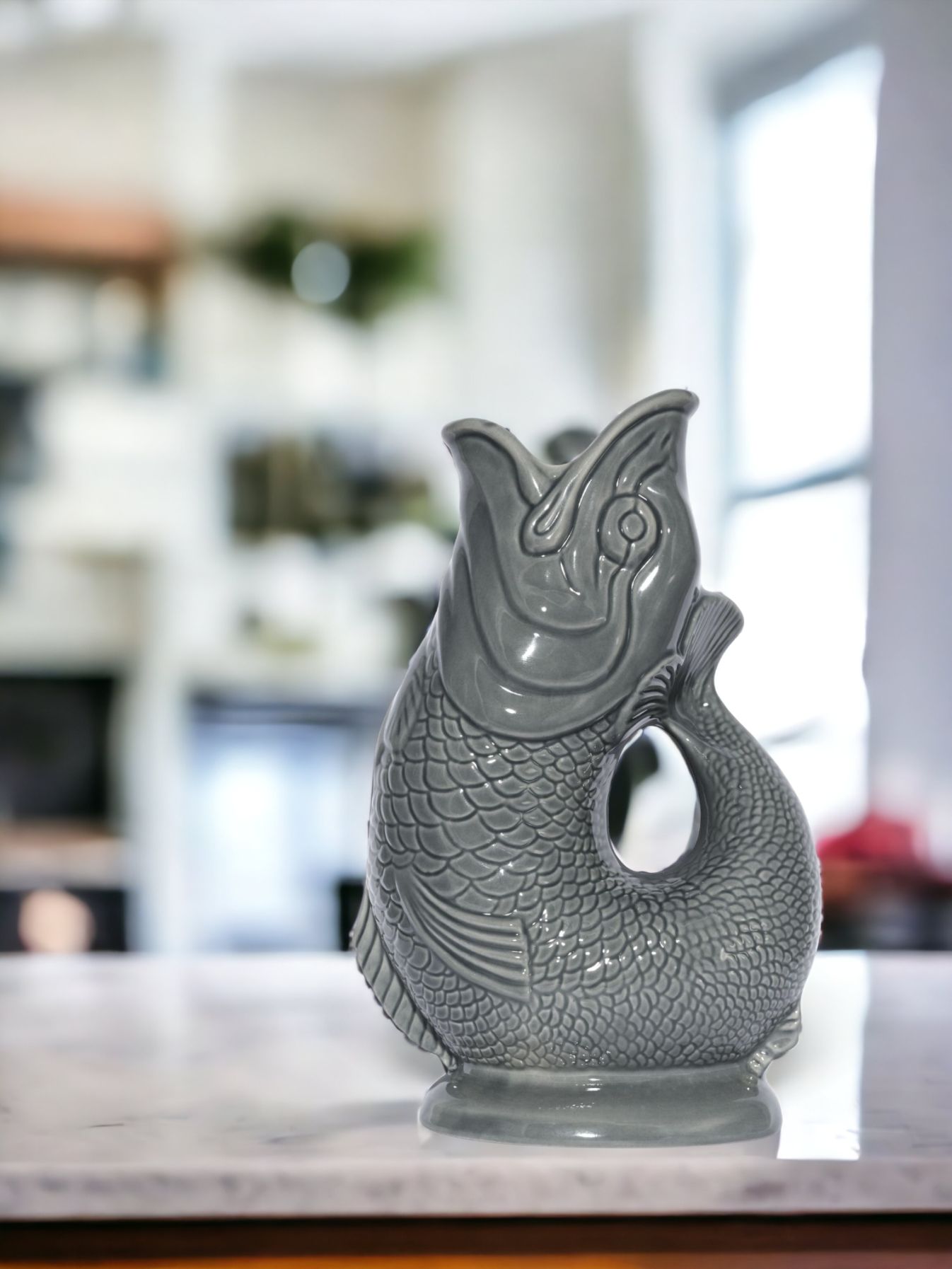 Dunkelgraue Gluckigluck Fischkaraffe XL auf Marmorplatte. Keramik Wasserkaraffe in Fischform. Dekorative Vase.