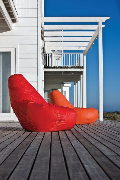 Roter und oranger Zanotta Sacco Sitzsack auf einer Holzterrasse vor einem weißen Haus.