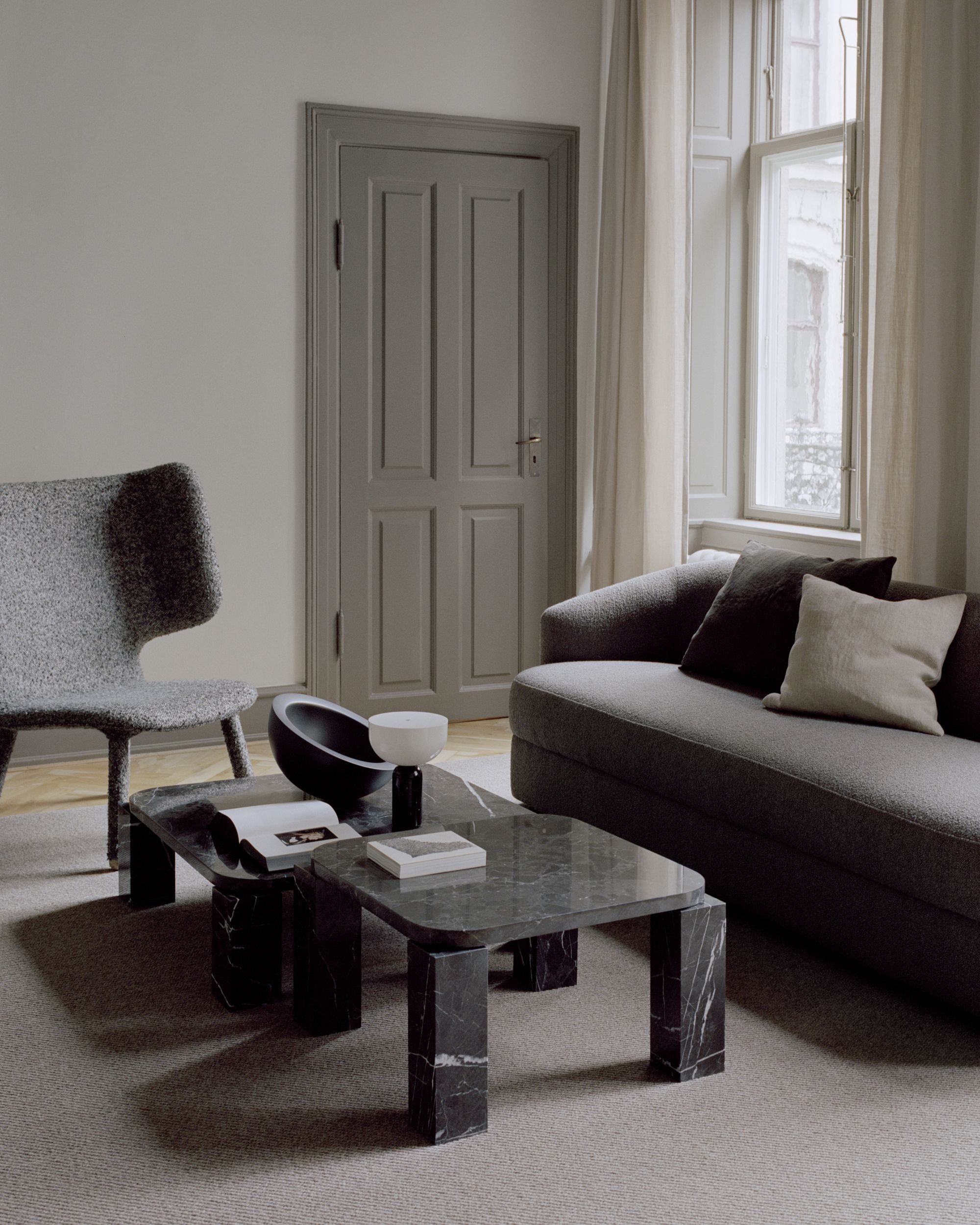 New Works Atlas Couchtisch 600x600 Costa Schwarz im Wohnzimmer mit Sofa und Sessel.