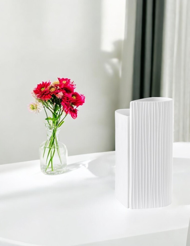 Weisse, plissierte Vase aus dem Hochzeit Vasen Set neben einem Blumenstrauss in Glasvase.