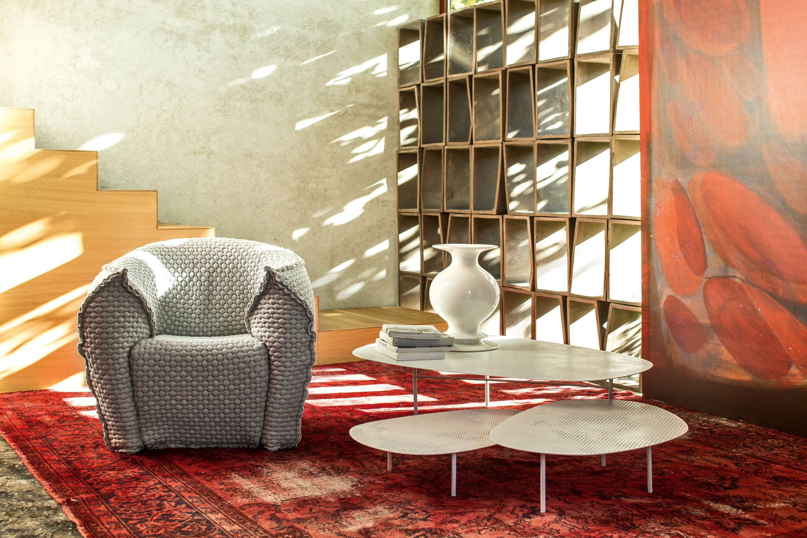 Grauer Cloud Tisch von Moroso mit zwei Ebenen, kombiniert mit Sessel und rotem Teppich.