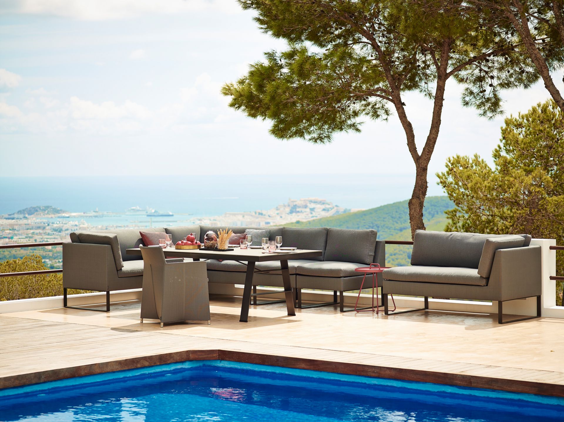 Graue Gartenmöbel-Loungegruppe mit Esstisch und Stühlen am Pool mit Meerblick. Hochwertige Outdoor-Möbel für Terrasse.