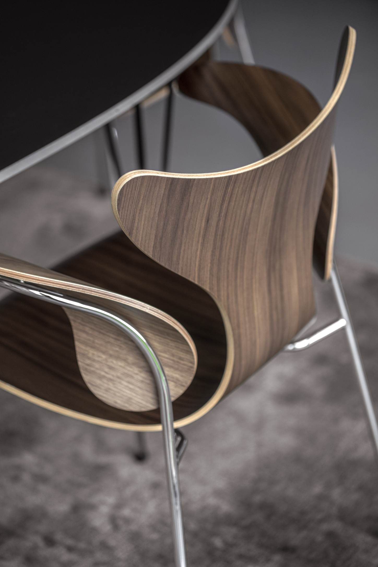 Detailaufnahme des Fritz Hansen Lily Stuhls mit Armlehnen, Holzschale und Chromgestell. Designklassiker für Esszimmer.