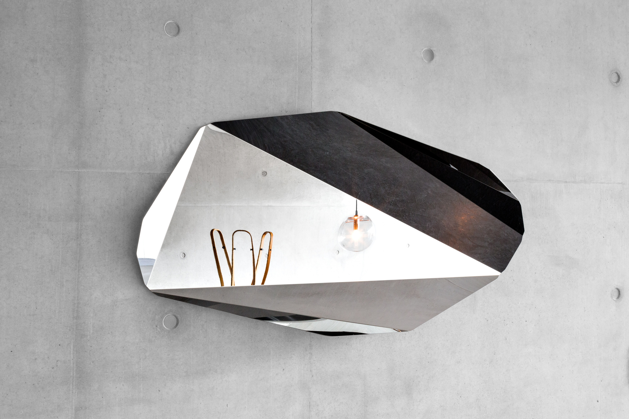 Piega Mirror Wandspiegel von Classicon, großer, facettenreicher Design-Spiegel an einer Betonwand. Modernes Wohnaccessoire.