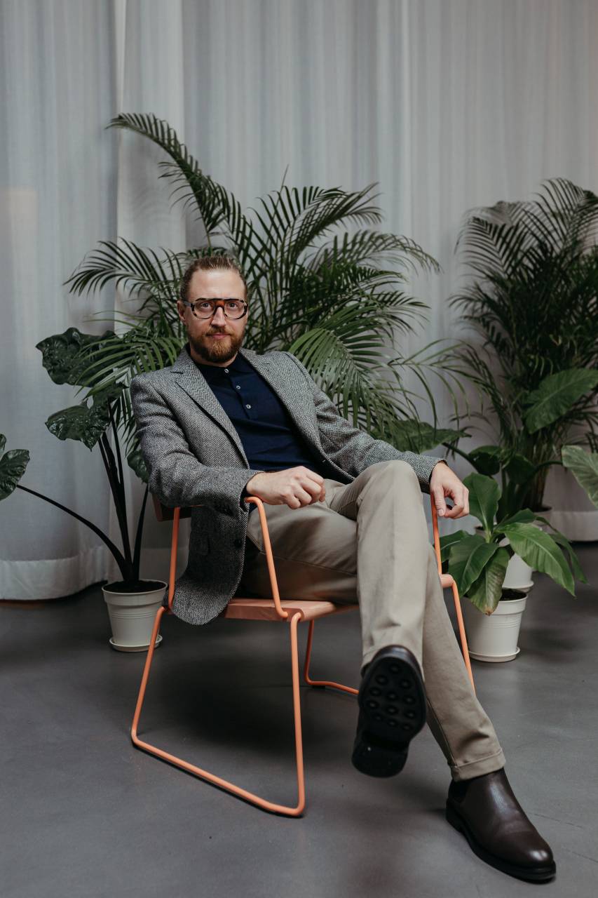 Mann sitzt entspannt im D:008 Loungechair von Fuchs & Habicht. Kohleschwarzer Sessel mit Armlehnen.