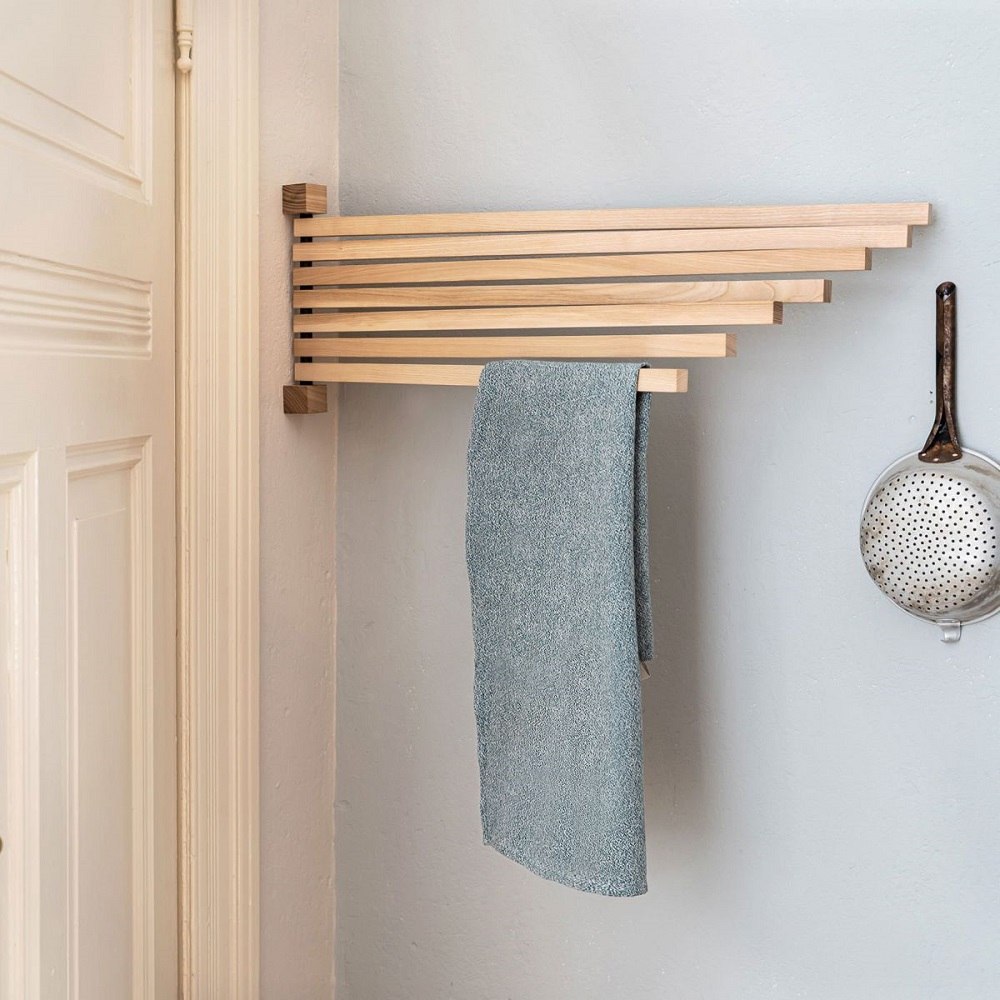 Pavo L Peacock Wandpfau: Handtuchhalter aus Holz mit blauem Handtuch an grauer Wand.