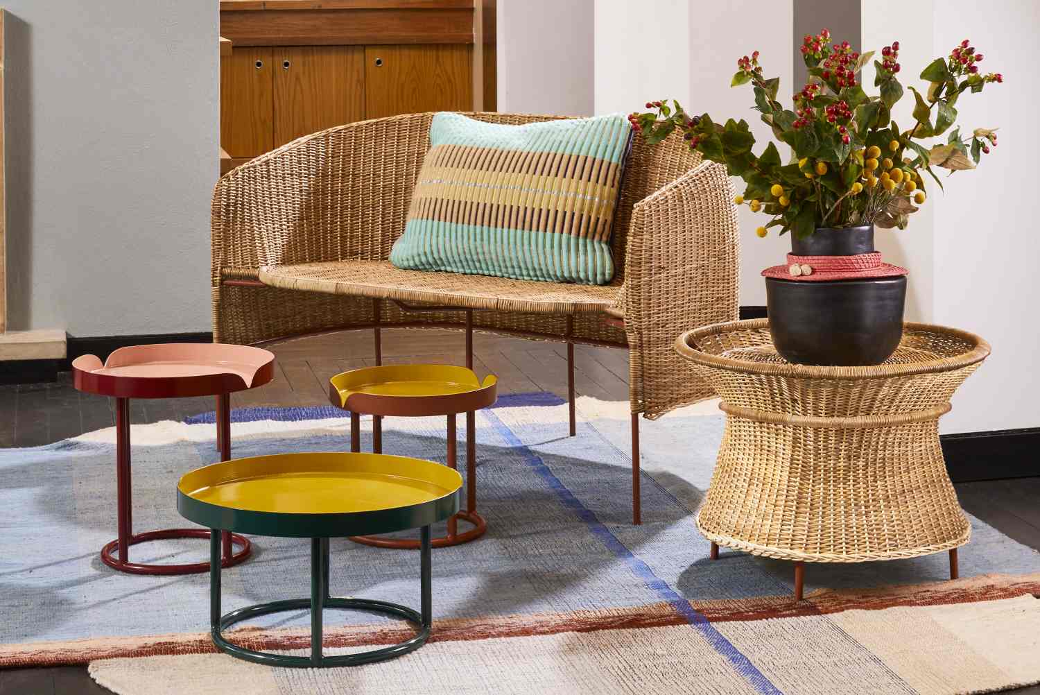 Caribe Basket Table aus Naturmaterial neben weiteren Outdoor Tischen und einem Korbstuhl.