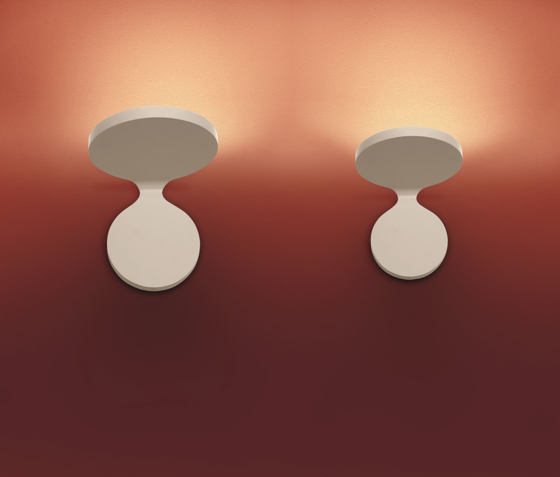 Zwei Rea Wandleuchten von Artemide an einer Wand, die warmes Licht abstrahlen.