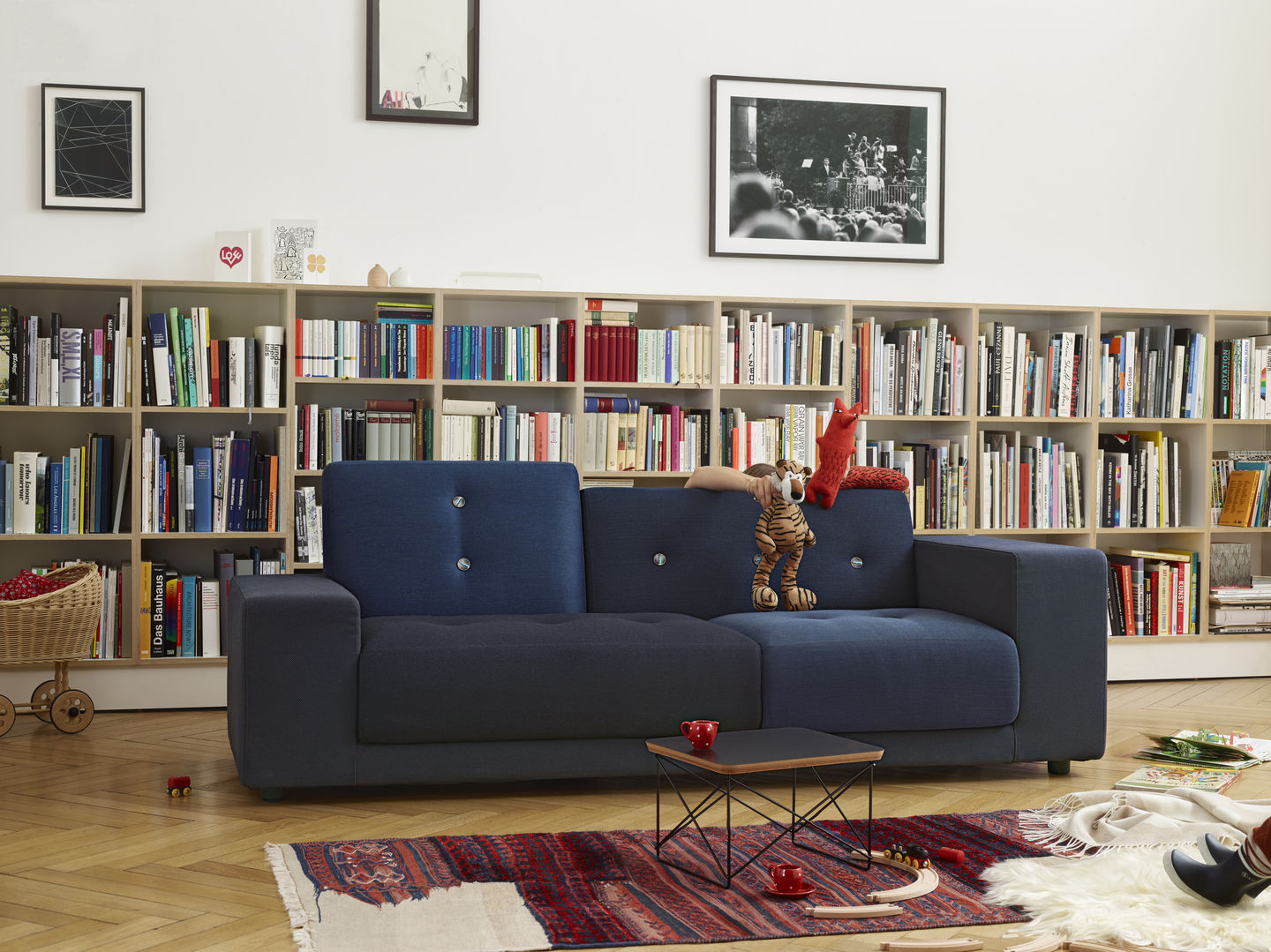 Blaues Polder Sofa von Vitra vor Bücherregal, mit Spielzeug dekoriert. Modernes Wohnzimmer Design.