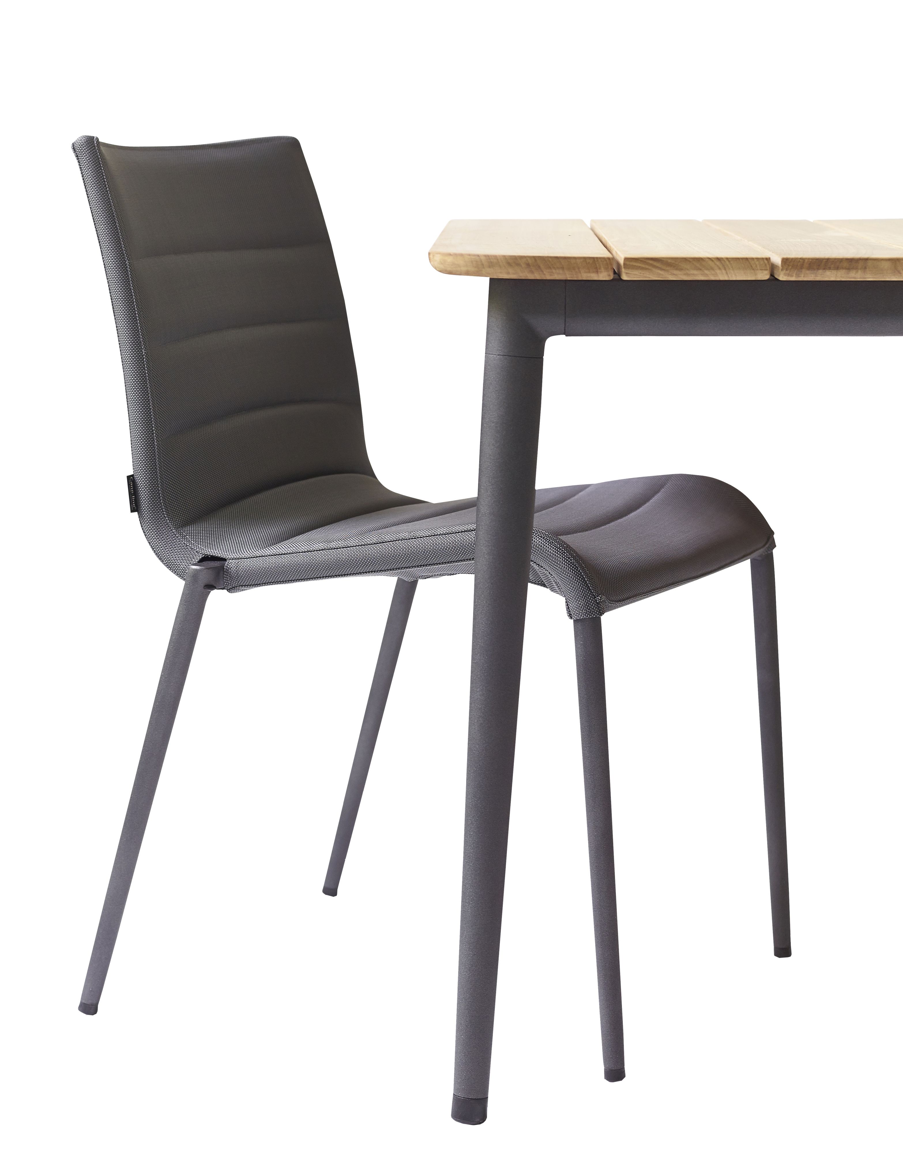 Cane-Line Core Outdoor Stuhl AirTouch in Grau neben einem Gartentisch mit Holzplatte.