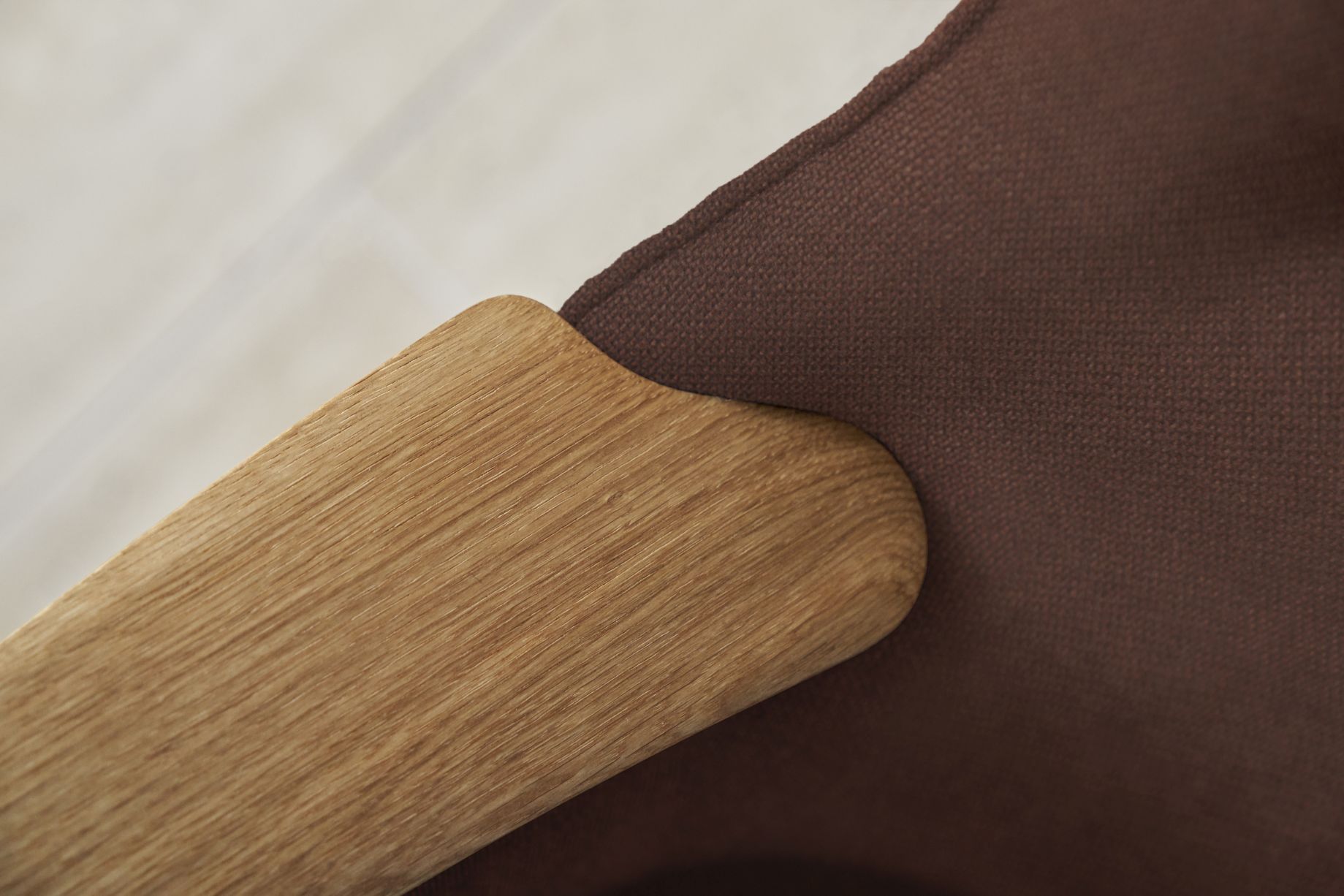Detailaufnahme: Holzarmlehne und roter Stoffbezug des CH78 Mama Bear Sessels.