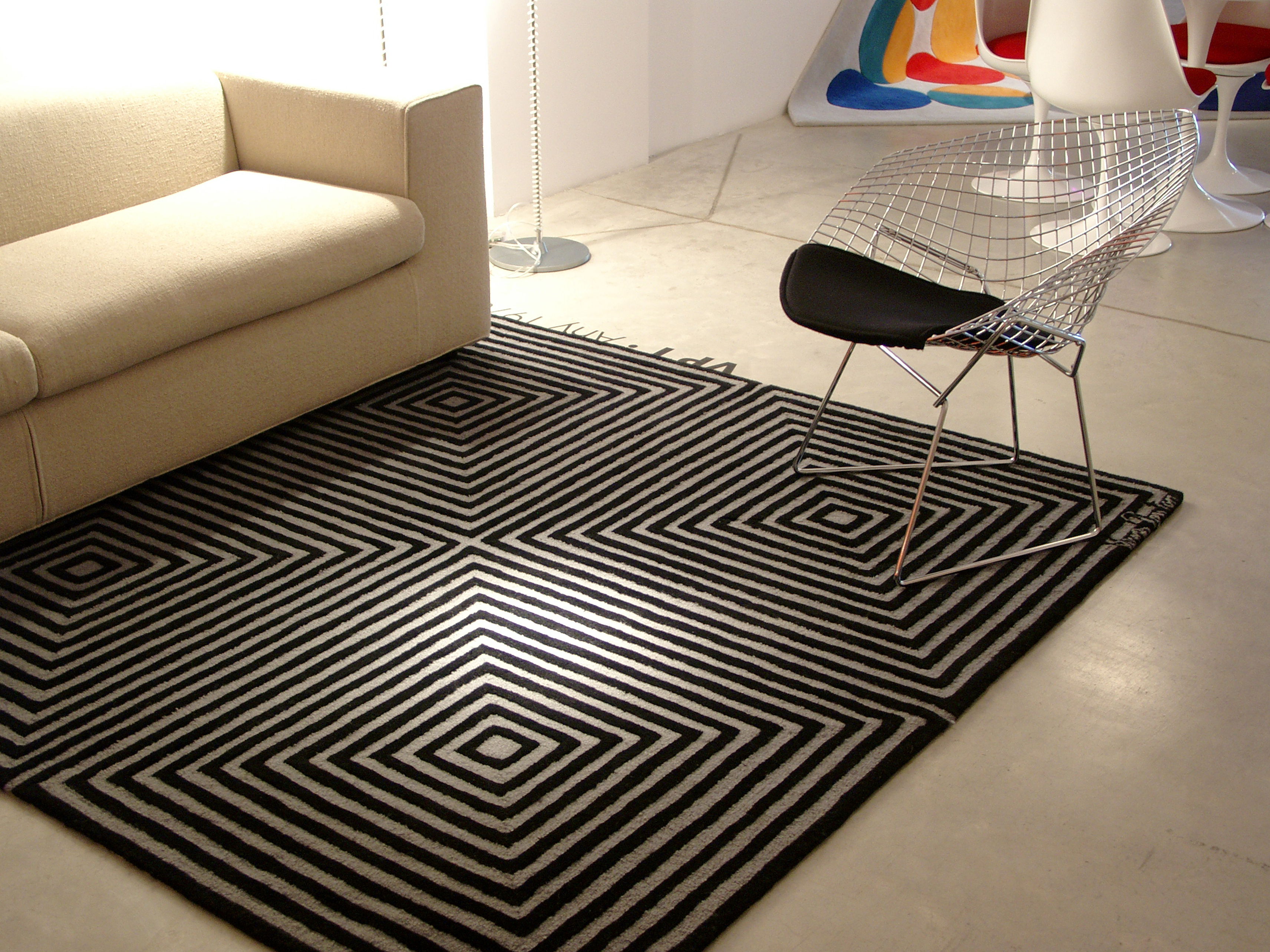 Panton Teppich mit grafischem Muster in Schwarz und Weiß, neben Sofa und Design-Stuhl.