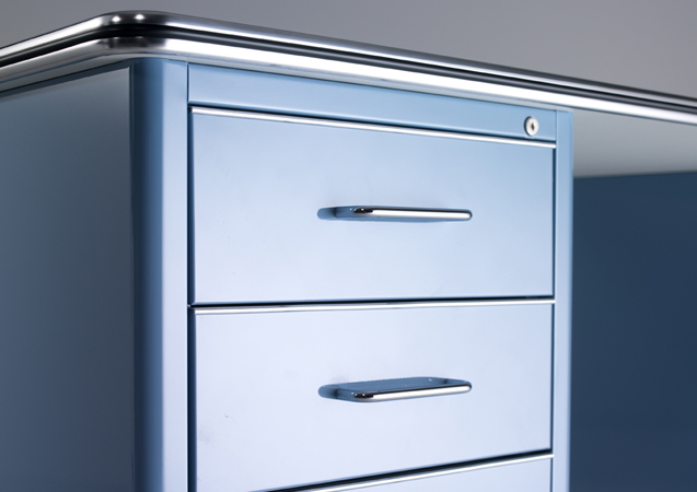 Detailaufnahme des blauen TB 228 Classic Line Schreibtischs von Müller Möbelfabrikation mit drei Schubladen und Chromgriffen.