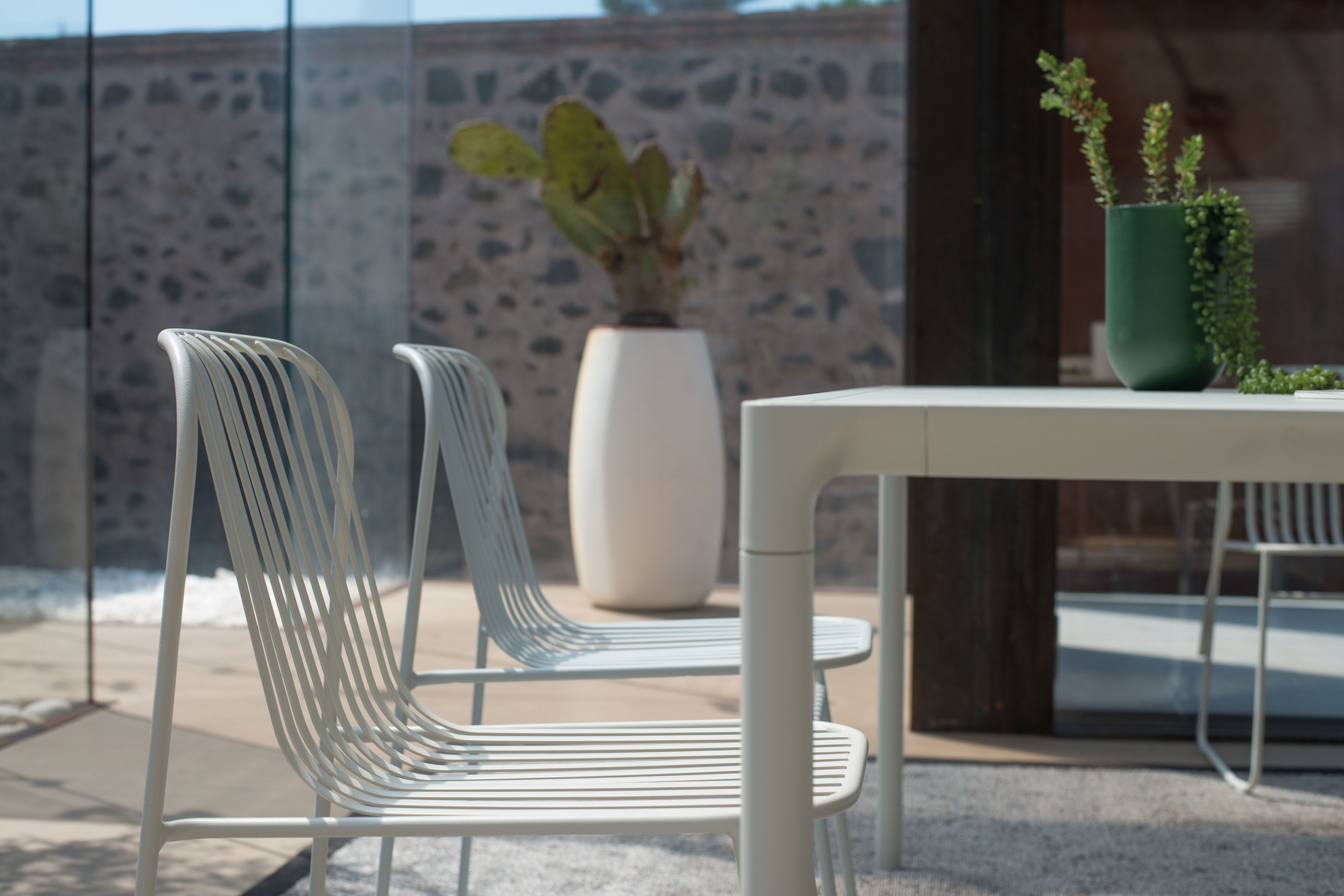 Riviera Stuhl in Antikes Eisen: Detailaufnahme von zwei modernen Metallstühlen für den Außenbereich.